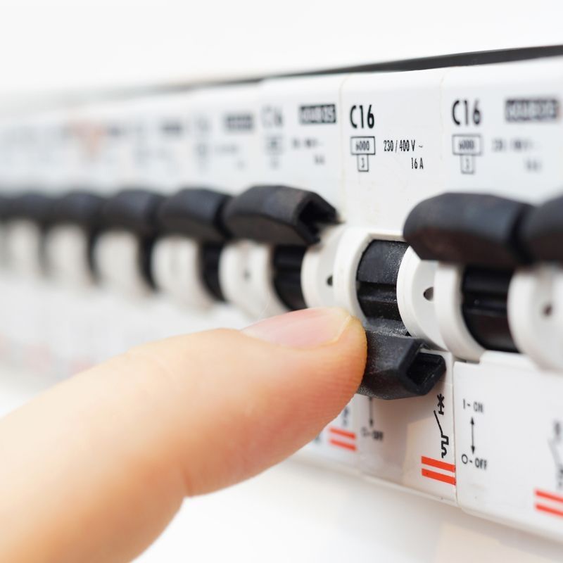 Eine Person betätigt einen Schalter an einem Strompanel zur Steuerung der Energiezufuhr.